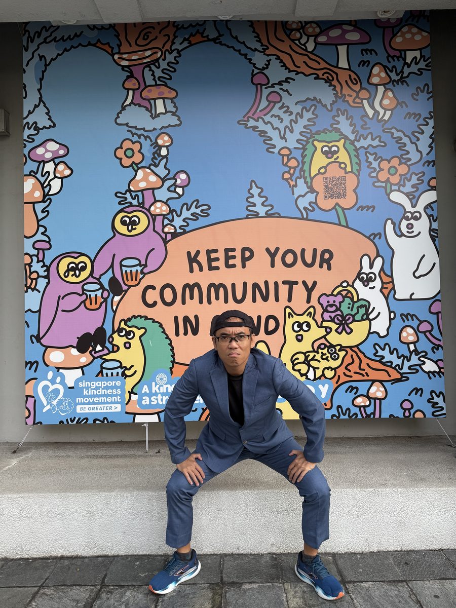 Runner Kao Singapore content creator at Singapore Kindness Movement mural in suit and running shoes